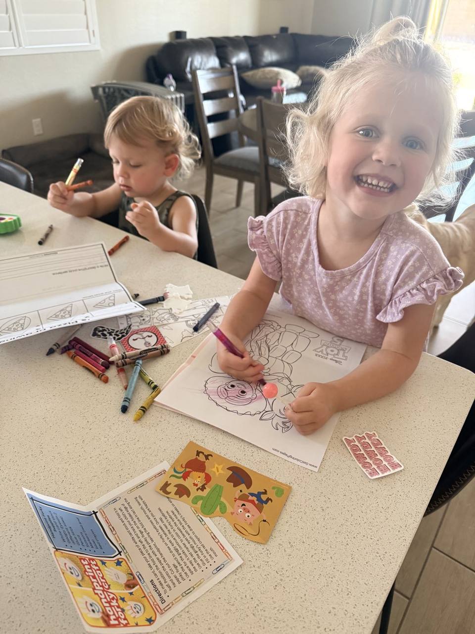 Two young children smiling while coloring their Mailbox Wonders activity sheets